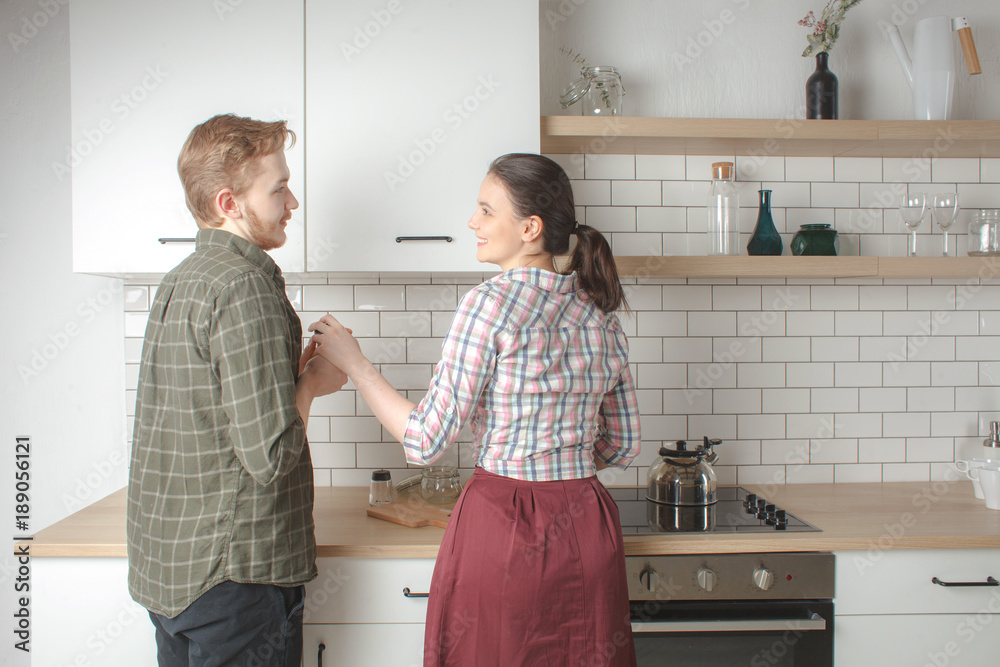 young boyfriend helps his girlfriend cooking at home kitchen interior