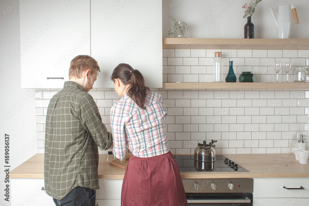 young regular couple cooking at home kitchen together, back view young regular couple cooking at home kitchen together, back view