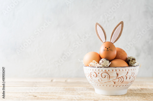 Wall Mural Easter bunny with eggs in bowl on grey background