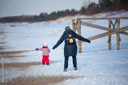 Little girl child is playing with the snow with gradmother in park in winter photo