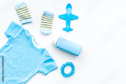Blue set for newborn boy. Baby bodysuit, socks, airplan toy and powder on white background top view copy space