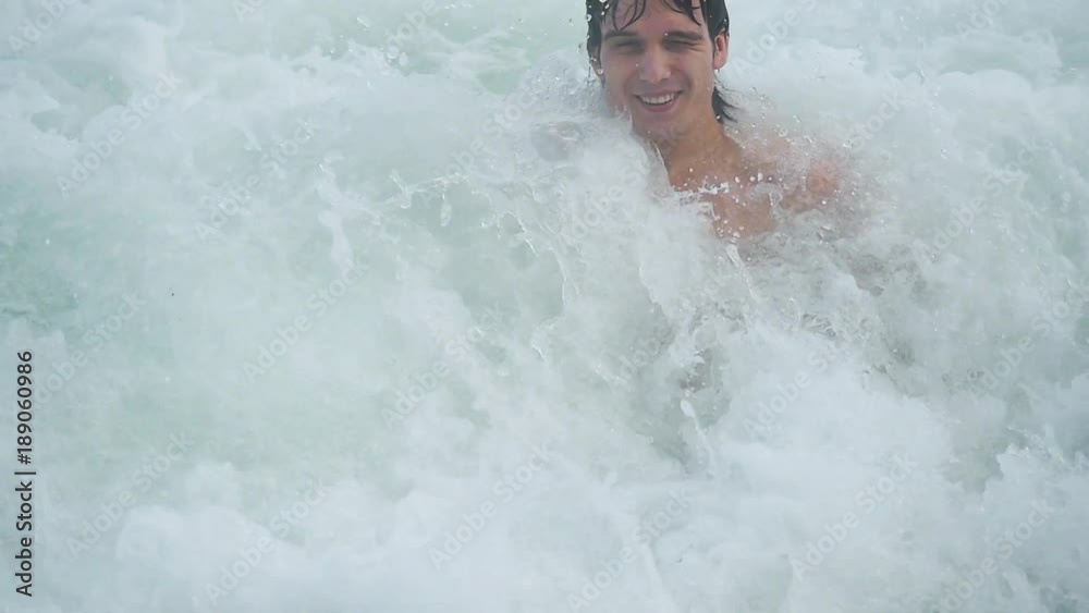 Young handsome happy man swimming in the sea and splashing wave in slow motion. 1920x1080 Young handsome happy man swimming in the sea and splashing wave in slow motion. 1920x1080