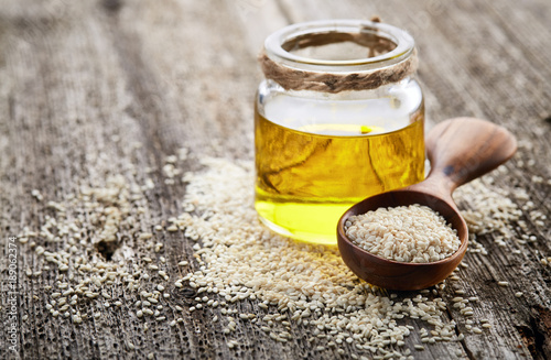 Sesame oil with seeds on wooden background