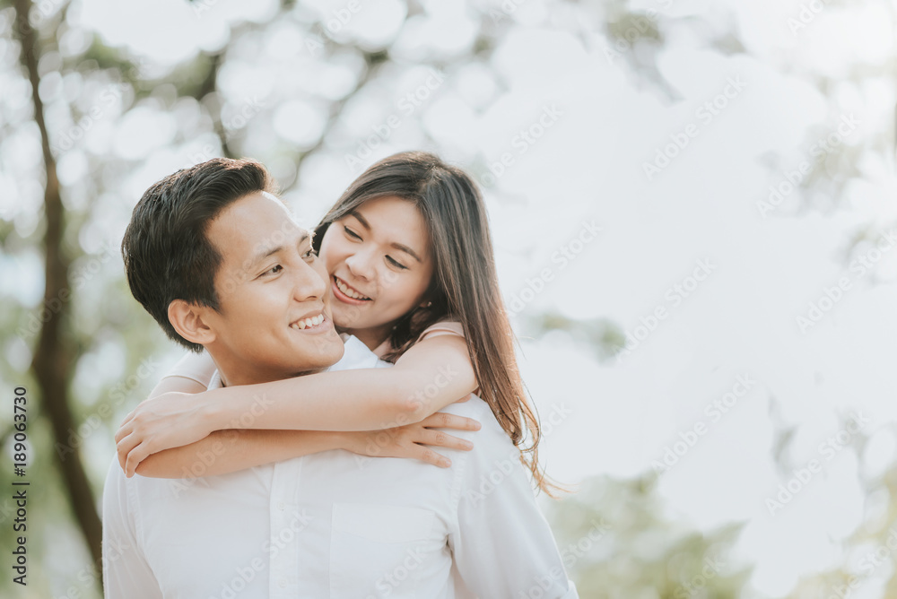 Happy young Asian couple in love having a good time and embracing in the park Happy young Asian couple in love having a good time and embracing in the park