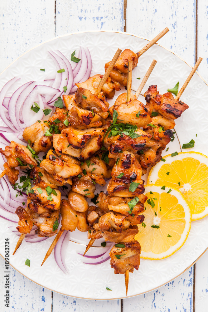 Chicken kebab with a lemon and onion on a wooden background.