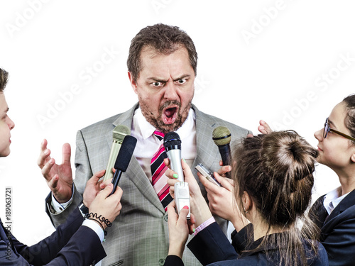 The politician speaks and gives interviews to journalists in a strong emotional excitement. Many microphones record it in front.