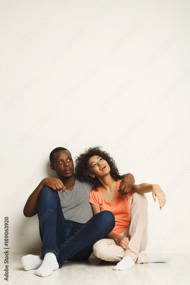 African-american couple looking up, sitting on floor