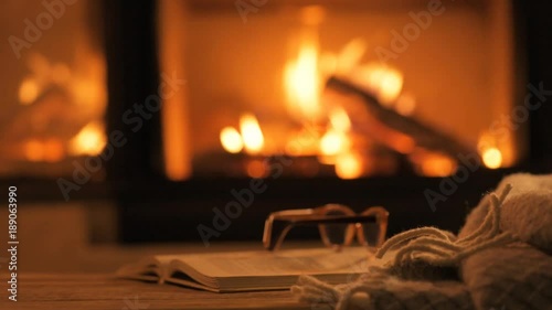 Young woman  sitting at home by the fireplace and drinking a mug of cocoa .