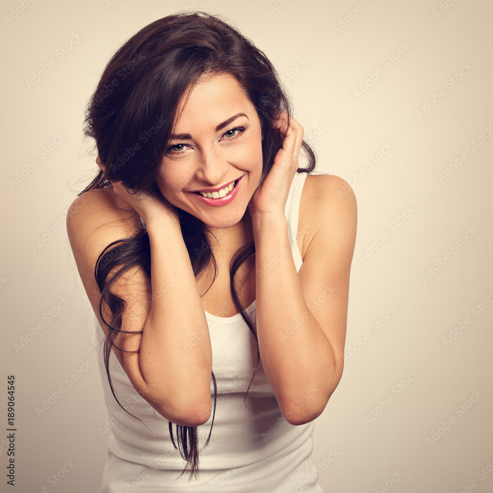 Beautiful positive laughing young woman in white shirt and long curly hair. Closeup toned portrait Beautiful positive laughing young woman in white shirt and long curly hair. Closeup toned portrait