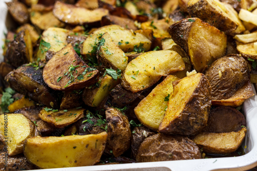Freshly fried potato wedges with herbs and garlic on a baking sheet Freshly fried potato wedges with herbs and garlic on a baking sheet