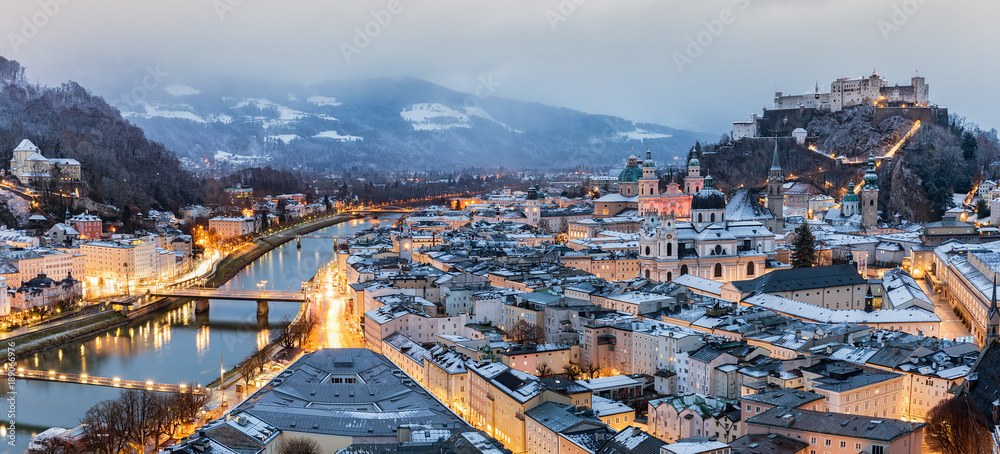 Obraz premium Widok na oświetlone stare miasto Salzburga w zimowy poranek