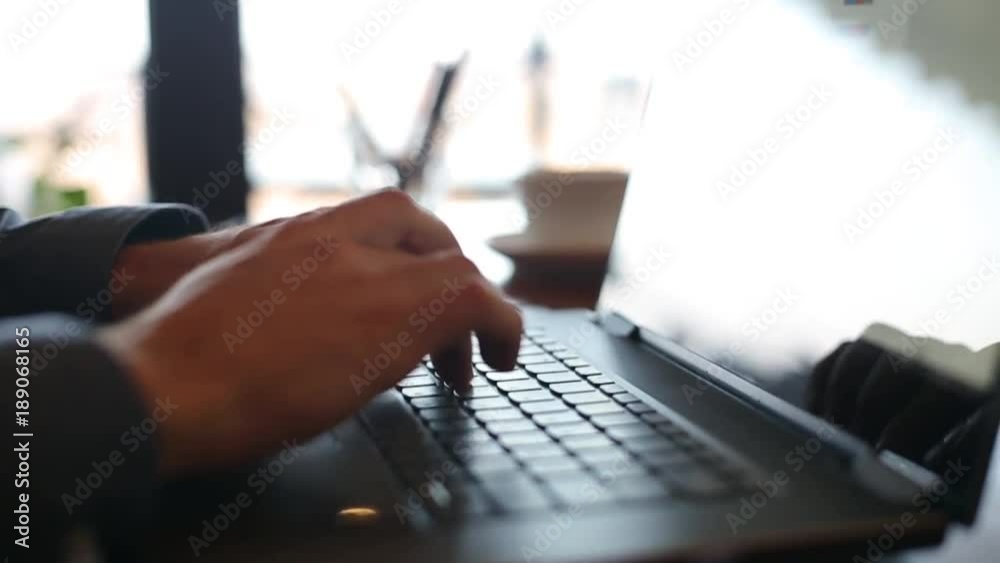 Camera slides around freelancer's hands typing on laptop keyboard in slow motion. Businessman working at office with internet. Man searches new job on internet at coffeeshop. Business concept.