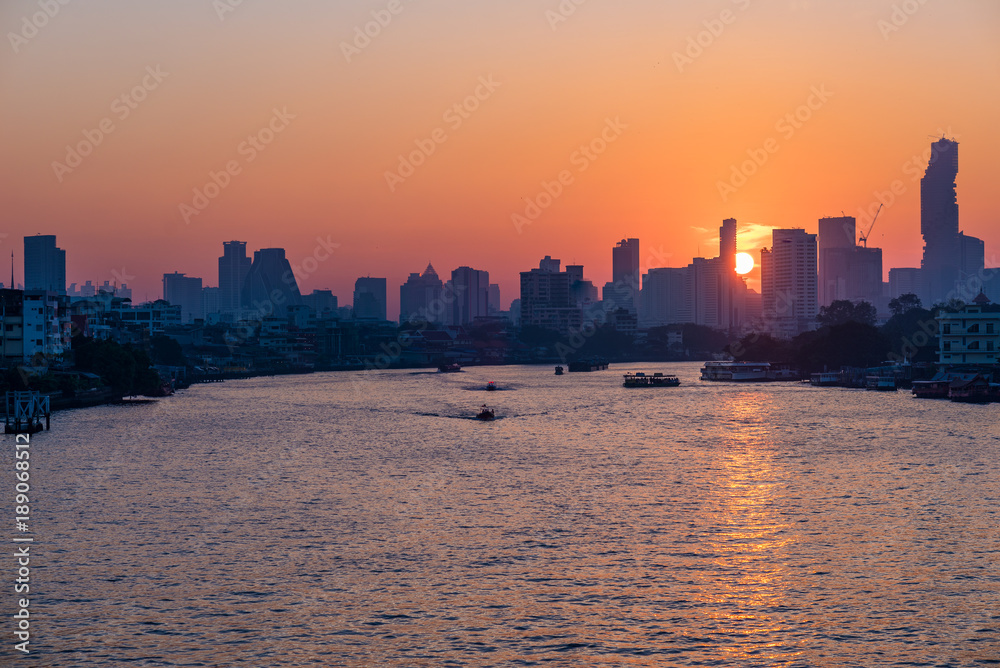 Bangkok skyline at sunrise, capital city of Thailand, scenic cityscape. Boats cruising on the Chao Phraya River.