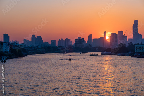 Bangkok skyline at sunrise, capital city of Thailand, scenic cityscape. Boats cruising on the Chao Phraya River. © fabio lamanna