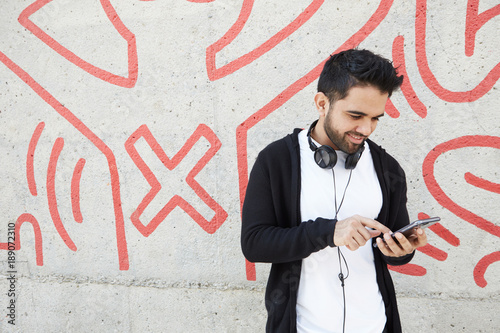 Attractive young man with cell smiling guy relaxing outdoors making mobile call, successful confident hipster having pleasant phone conversation. photo