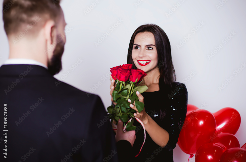 I congratulate you on the holiday of lovers. Smiling man giving flowers and gift to his happy woman on Valentine's Day. I congratulate you on the holiday of lovers. Smiling man giving flowers and gift to his happy woman on Valentine's Day.