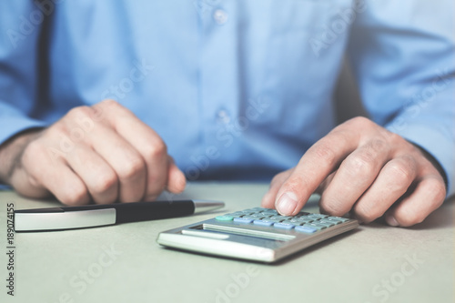 Businessman using calculator in his desk.
