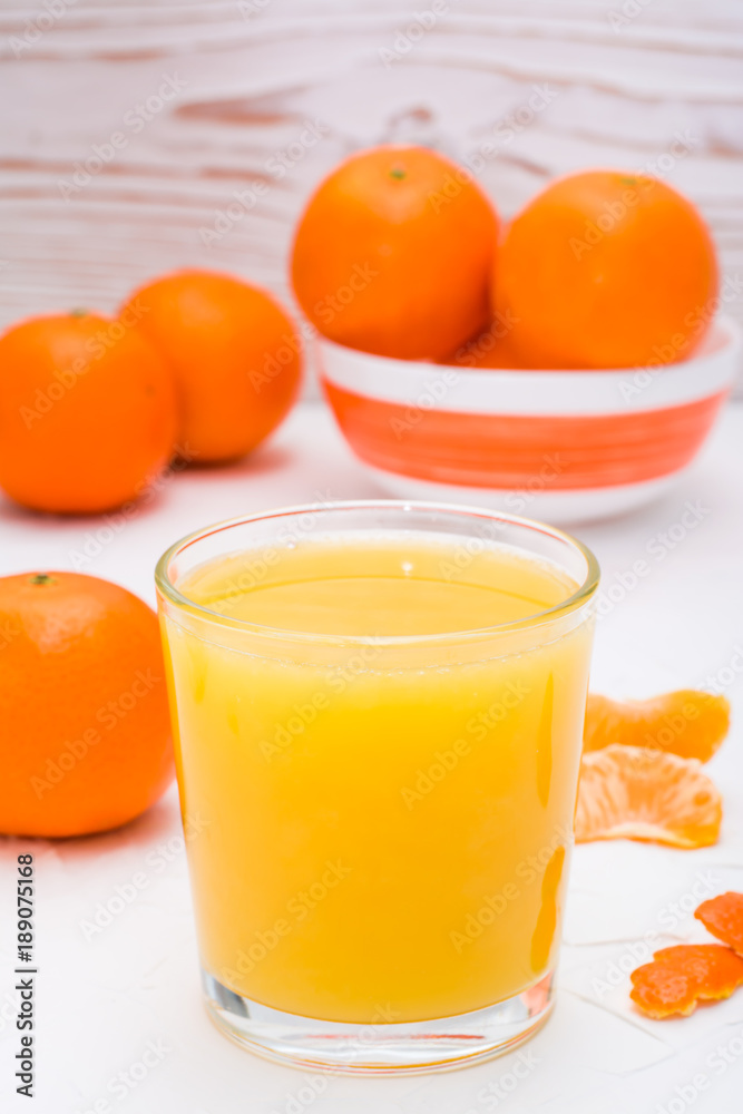 Mandarin juice in a glass and ripe mandarins on a table Mandarin juice in a glass and ripe mandarins on a table