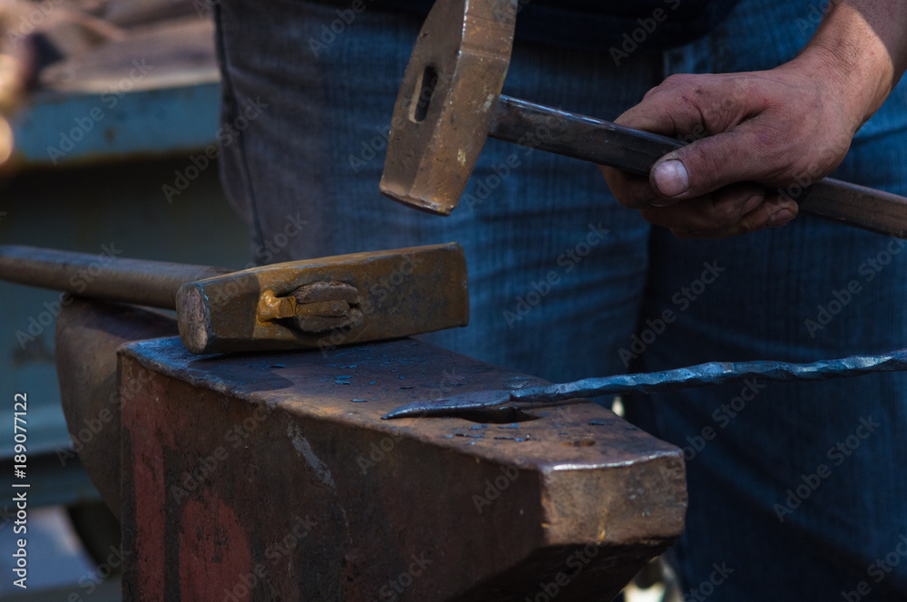 blacksmith performs the forging of hot glowing metal on the anvil