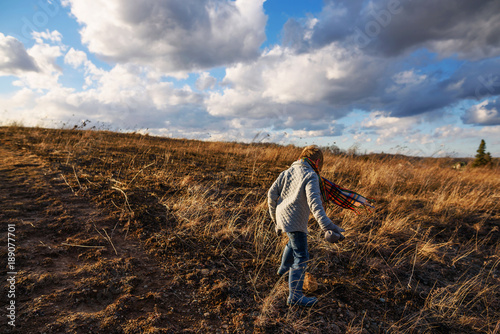Boy walking through a field on a windy day