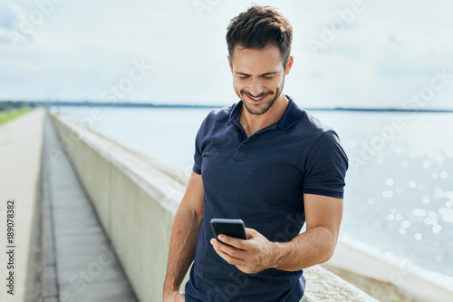 Happy man texting on his phone outdoors photo