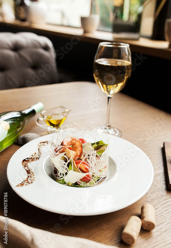 beautiful salad with seafood with a glass of white wine on a wooden table