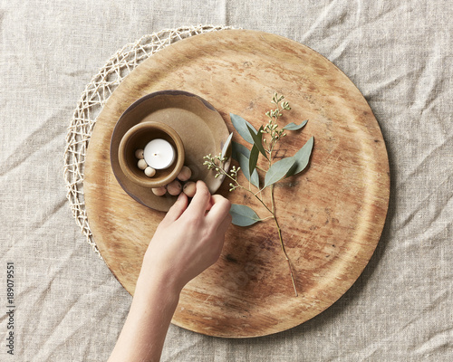 Hand arranging a candle and simple decor with leaves