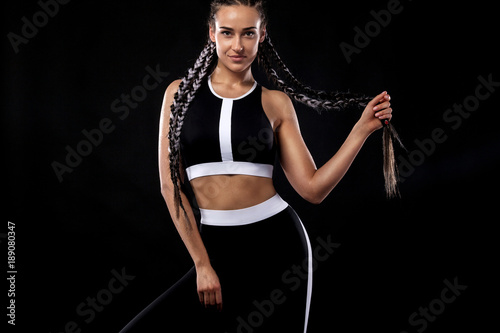 A strong athletic woman on black background wearing in black sportswear, fitness and sport motivation. Sport concept with copy space.