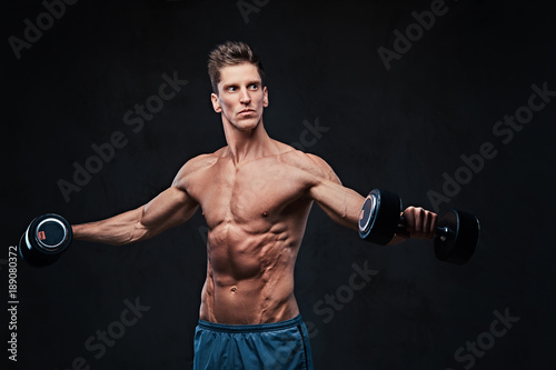 Shirtless athletic male doing shoulders exercises. © Fxquadro