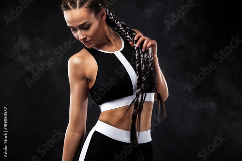 A strong athletic woman on black background wearing in black fashion sportswear, fitness and sport motivation. Sport concept with copy space.