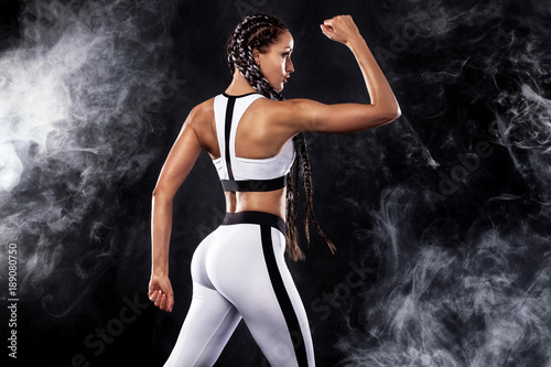A strong athletic woman on black background wearing in white sportswear, fitness and sport motivation. Sport concept with copy space.