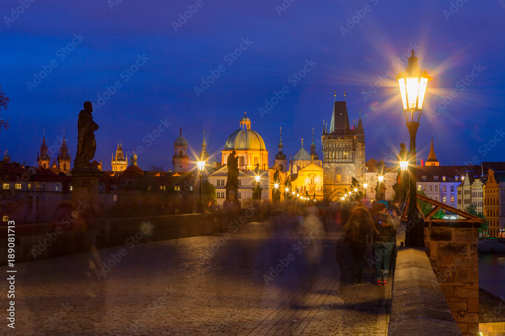 Summer night walking by illuminated Charles Bridge, Prague, Czech Republic