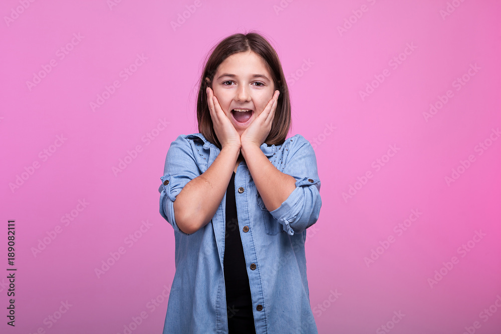 Suprised girl holding her hands on the face on pink background in studio Suprised girl holding her hands on the face on pink background in studio