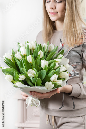 beautiful luxury bouquet of white tulips flowers in woman hand. the work of the florist at a flower shop. cute lovely girl