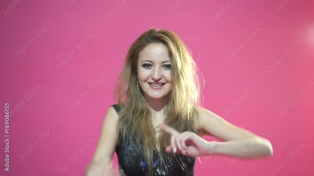 Happy woman is singing and dancing against a pink background Happy woman is singing and dancing against a pink background