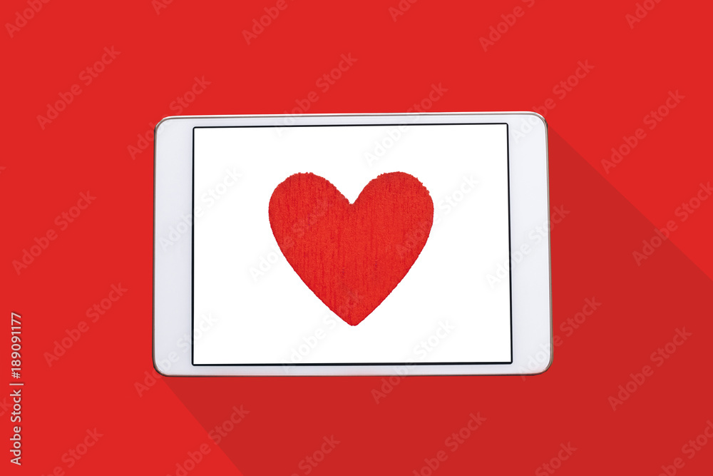 Top view. Red heart on the tablet screen. Top view. Red heart on the tablet screen.
