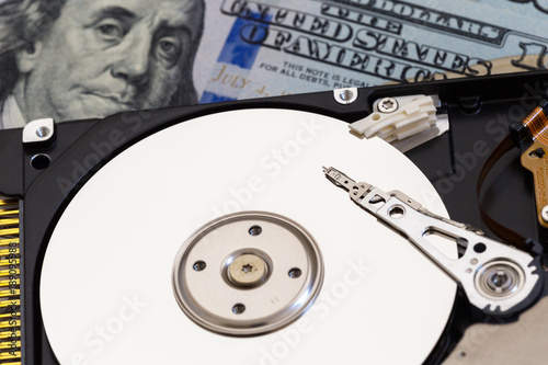 disassembled hard drive on money background. Concept of data recovery
