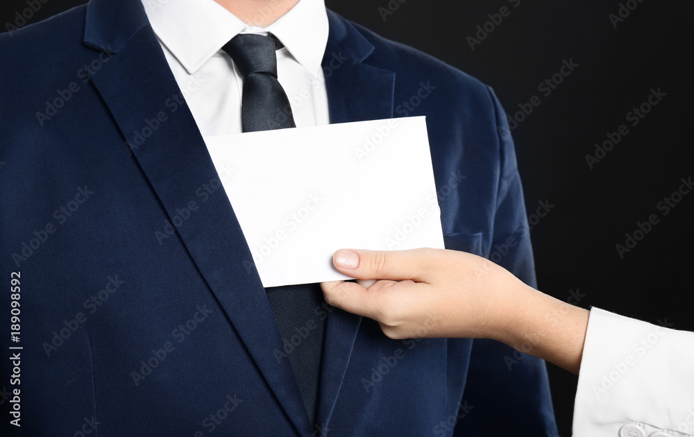 Woman putting envelope with bribe in businessman's pocket, closeup
