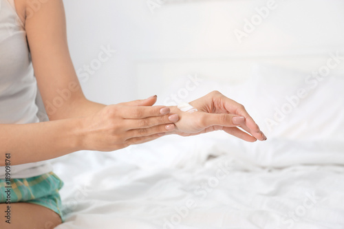 Young woman applying hand cream at home
