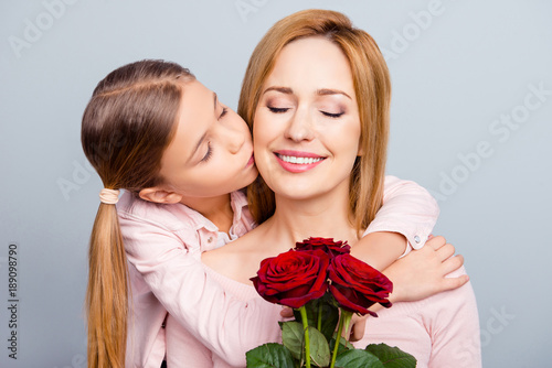 Trust care motherhood maternity parenthood people emotions kindness concept. Close up portrait of sweet cute lovely adorable gentle child giving kiss to beautiful calm mum isolated on gray background