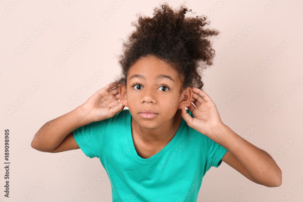 Little African-American girl with hearing problem on light background Little African-American girl with hearing problem on light background