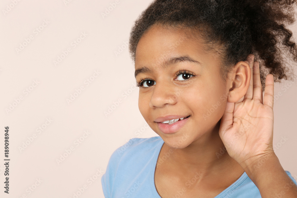 Little African-American girl with hearing problem on light background Little African-American girl with hearing problem on light background