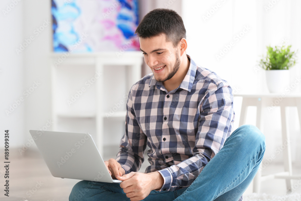 Young man using modern laptop at home Young man using modern laptop at home