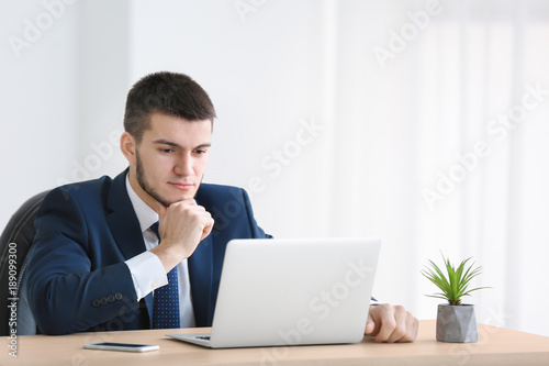 Young man in suit using lap...
