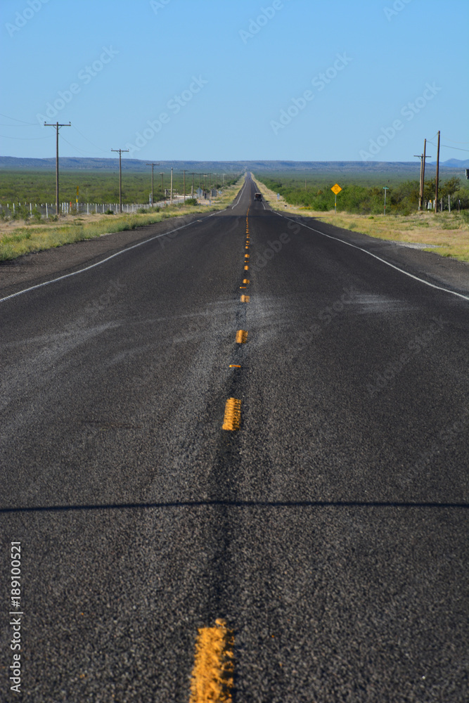 A lonely highway stretches off strait to the horizon in West Texas.
