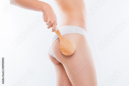 Smooth clean clear flawless soft neat slim underwear lingerie concept. Side view cropped close up photo of slim beautiful thin woman's body, hand holding wooden brush isolated on white background