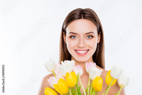 Wellness vitality womanhood no plastic surgery concept. Close up portrait of attractive gorgeous woman with pure ideal flawless smooth sensitive skin holding yellow white tulips isolated on background