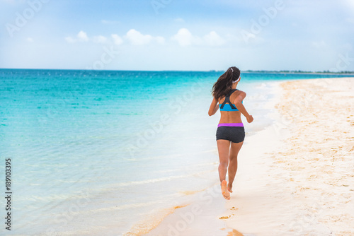 Fitness sports athlete woman runner jogging on Caribbean beach vacation destination. Running girl living an active and fit lifestyle on holiday. Cellulite weight loss concept.