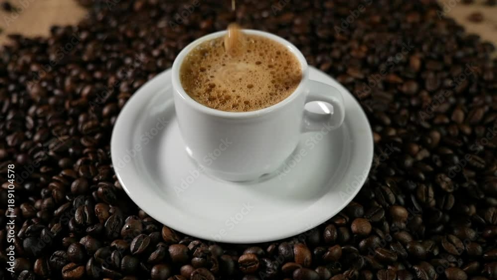 Coffee cup and coffee beans. A white cup of evaporating coffee on the table with roasted bean. Slow Motion coffee pour. Coffee cup and coffee beans. A white cup of evaporating coffee on the table with roasted bean. Slow Motion coffee pour.