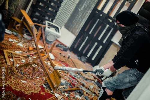 man in the rage room smashing chair and old computer with a baseball bat photo